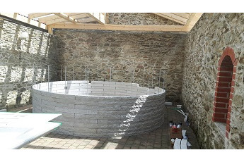 Hrubá stavba kruhového bazénu v designu štípaného kamene