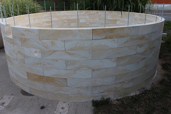 Hrubá stavba kruhového bazénu v designu řezaného pískovce